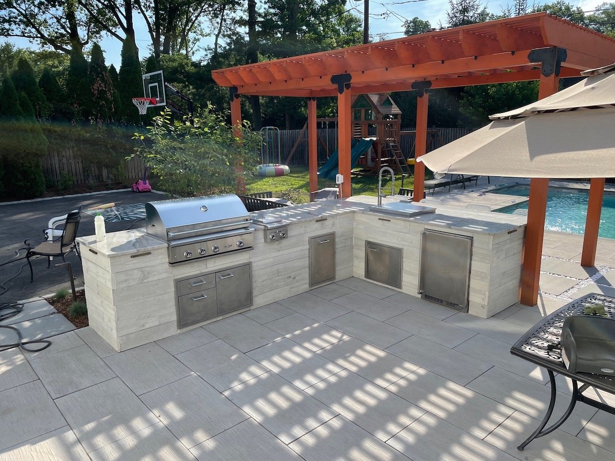 Outdoor kitchen with full grill, sink, refrigerator and pergola poolside.JPEG